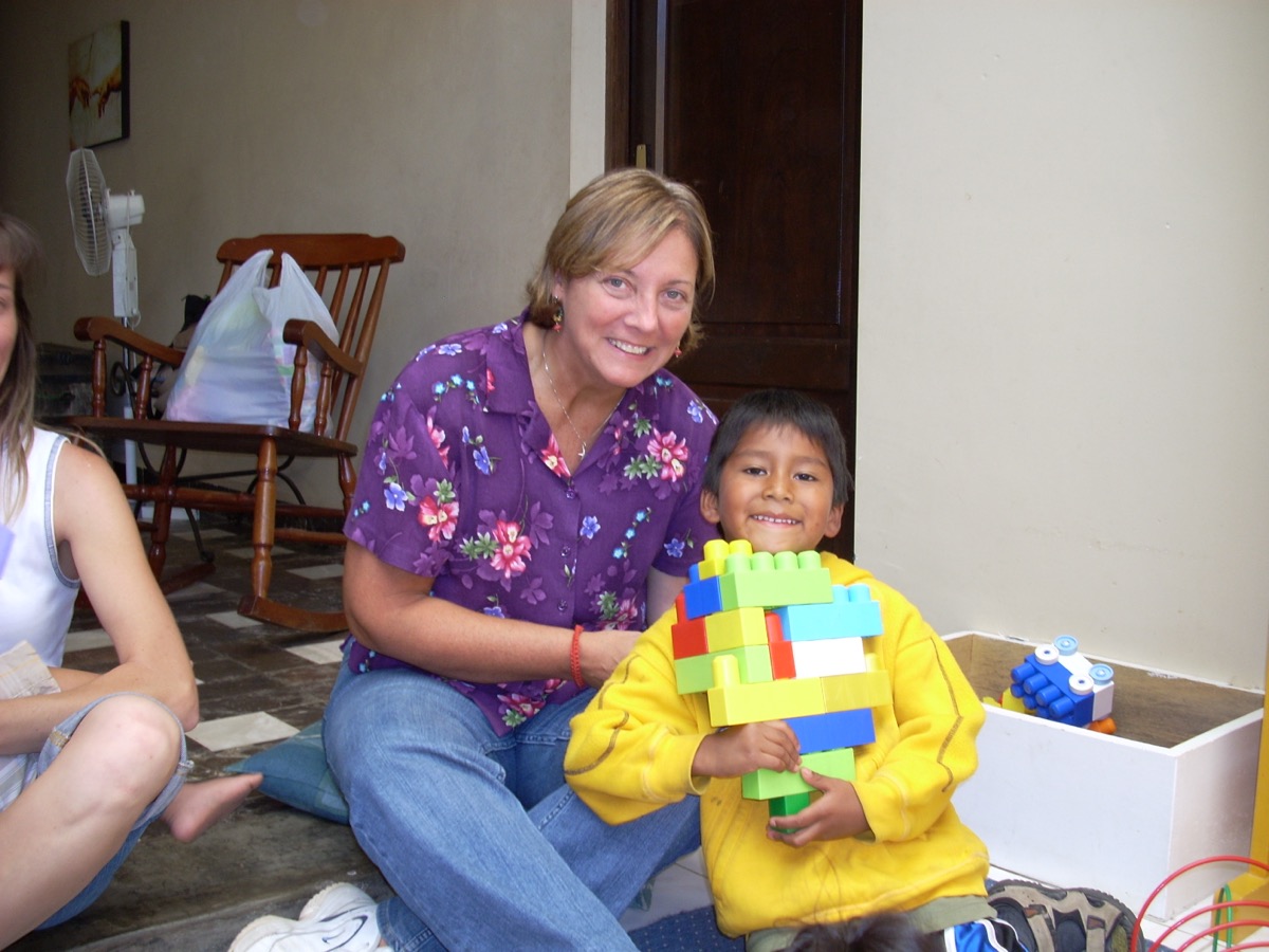 Mollie sitting with a boy who is holding a toy he has built